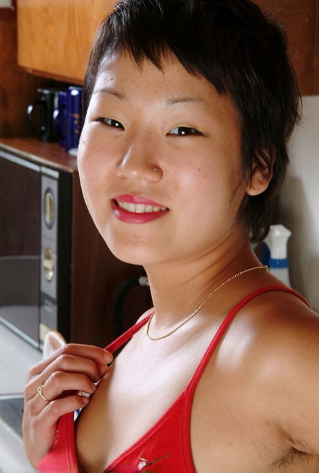 Petite Asian girl with short hair plays with her bush after uncovering her tits