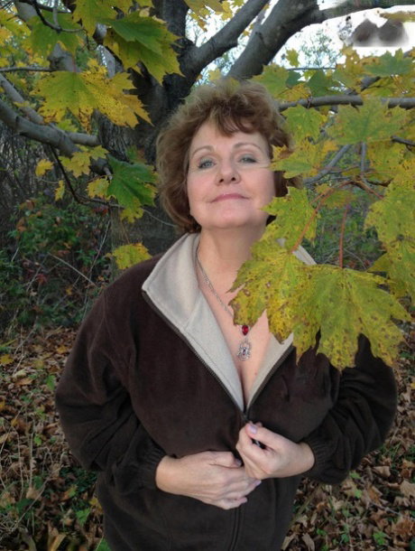 Older woman Busty Bliss exposes her big natural tits under a tree in the fall