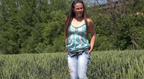 Older brunette NicolD whips down her blue jeans to piss in the tall grass