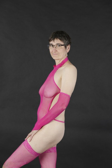 Mature amateur gets naked in pink arm socks and stockings with her glasses on