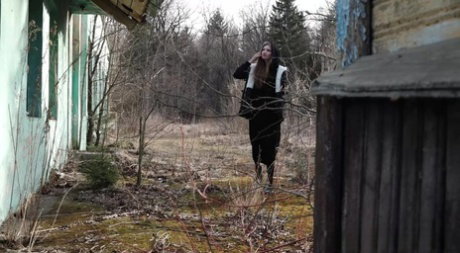 Solo girl pulls down black hose before squatting to pee beside a building