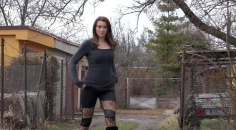 Victoria Daniels squats for a piss outside a garage door during the day