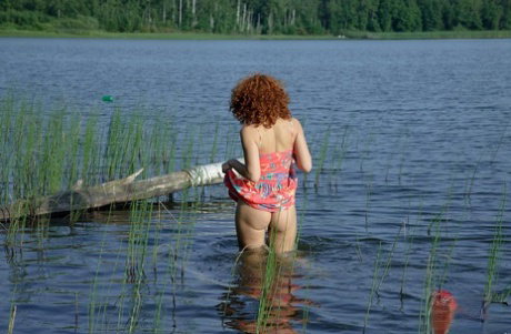 Solo girl Sunny exposes her perky little teen tits on a log in the water