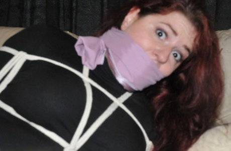 Helpless female struggles against her restraints while hogtied and silenced