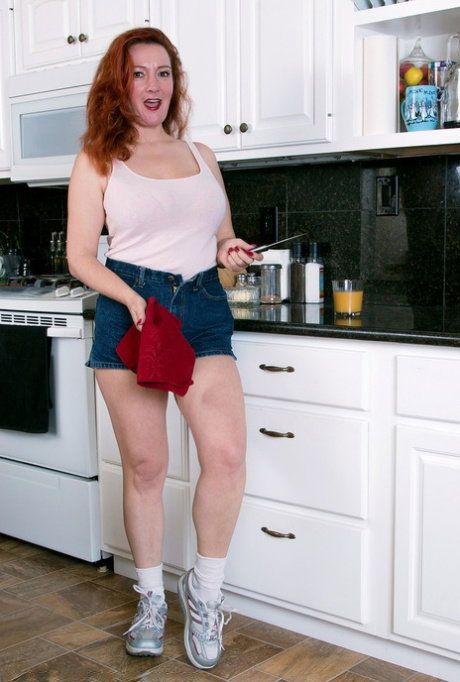 Older redhead Jessica OHare shows her big naturals and trimmed pussy in kitchen