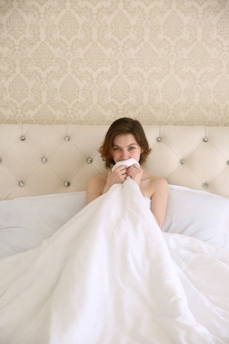 Young looking girl removes a towel to get completely naked on a bed