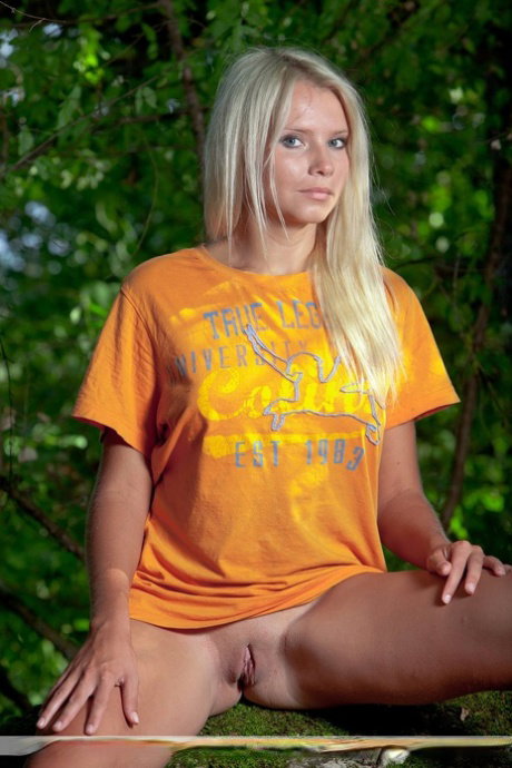 Natural blond Erra D remove a T-shirt to model naked in a tree