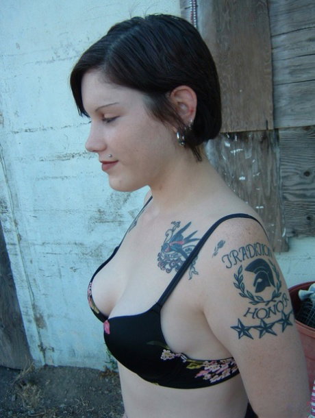 Cute emo chick covered with tattoos shows off her ass in black stockings