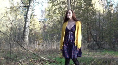 Redheaded girl Alexa pulls down her hose for a piss by a building in the woods