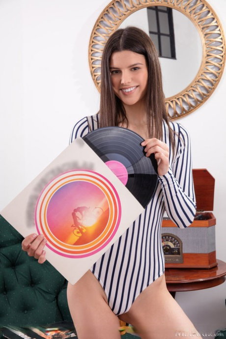 Sweet teen Viola Kat removes a bodysuit to get naked amid a record collection