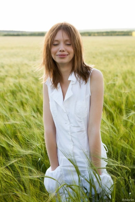 Naked teen with red hair roams a crop field during solo action