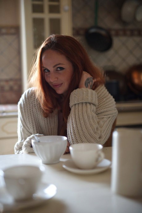 UK redhead Kara Carter rubs cream into her big natural tits in the kitchen