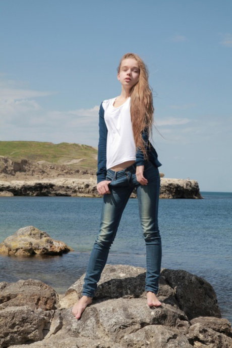 Slim teen gets caught in the act of removing her see thru dress on boulders