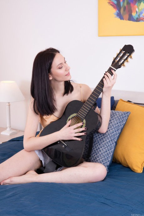 Nice teen with a fuzzy muff displays her naked body while playing a guitar