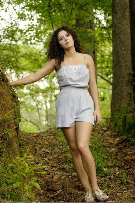 Solo girl with curly hair displays her thick bush in the forest