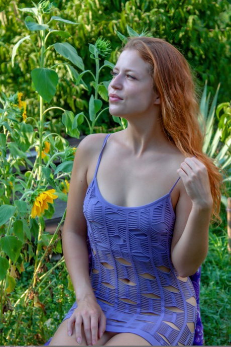Natural redhead removes a see thru dress to pose nude in a garden