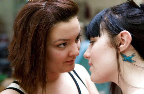 Coed lesbians Cassie and Keilyn sharing deep tongue kiss outdoors