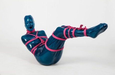 Fetish model Ropemarks is encased in latex clothing while bound with pink rope