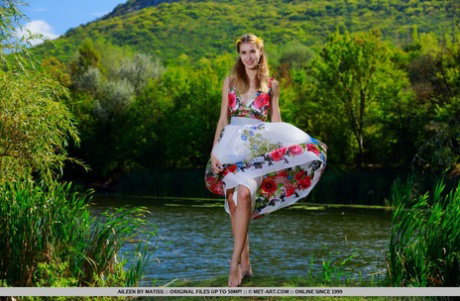 Skinny teen Aileen removes her dress to pose nude near a river