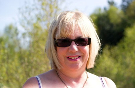 Blonde granny gets naked in sunglasses and stockings in a backyard