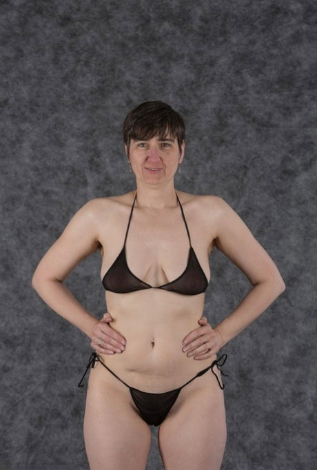 Short haired amateur holds her boobs after taking off a black bikini