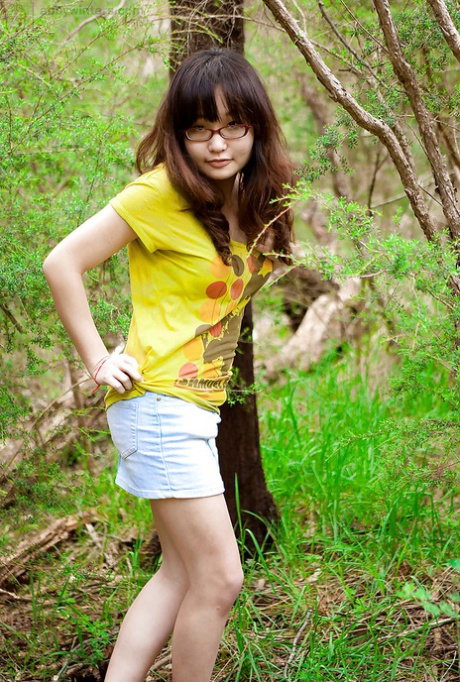 Petite Asian girl in glasses bares hairy vagina outdoors after slow strip