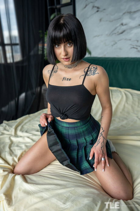 Tattooed teen Sarah Heizel inserts a black dildo into her shaved pussy
