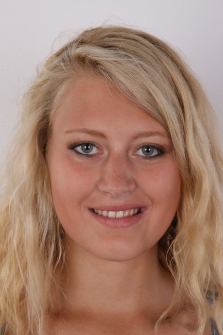 Blonde amateur with a pierced belly button stands naked after undressing