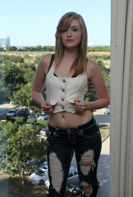 Petite young Mandy bares her small tits and slips her jeans off in the window