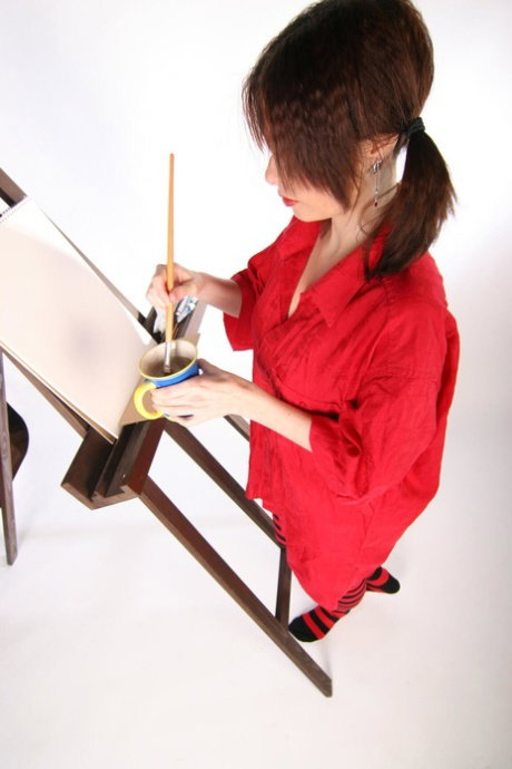Amateur model gets naked in striped thigh highs while painting at an easel