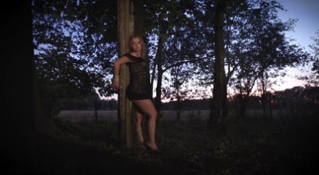 Blonde girl Alexa Flexy is suspended between trees in the dark of the night