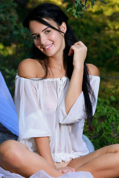Petite teen Lola Marron gets bare naked on a bedsheet in a forest
