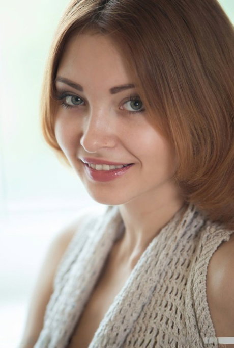 Young redhead Kika sets her great body free of clothing in front of a window