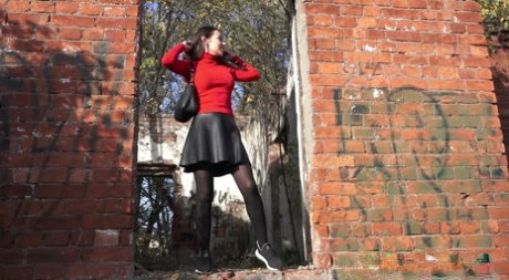 Pretty girl Sasha squats for a pee by a brick building in pantyhose