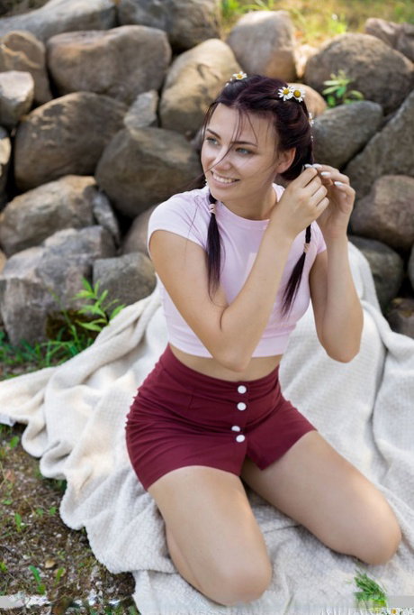 Brunette teen Nana tugs on her pigtails after going nude in the outdoors