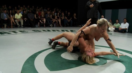 Naked girls participate in a wrestling match before posing naked on the mat