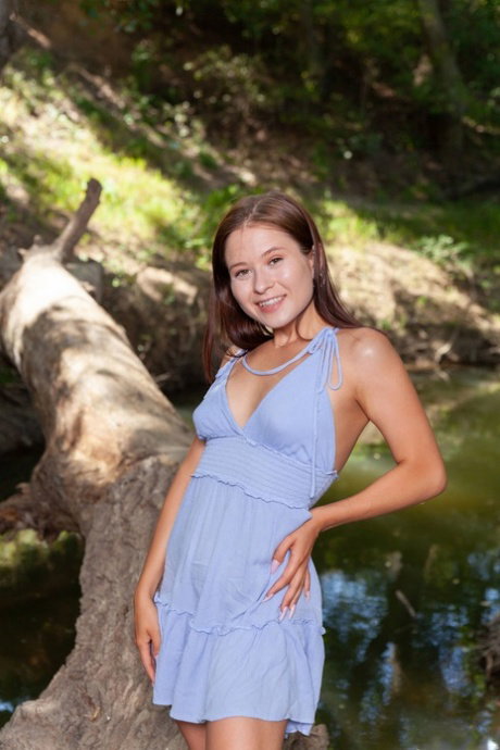 Young looking girl gets totally naked on a fallen log in the woods